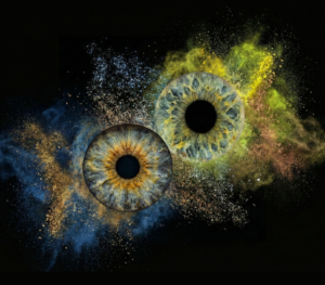 Soft "Iris Art online" piece "Soft Collision": two human eye irises (brown and light grey) surrounded by a powerful yellowish and bluish dust cloud effect against a black background. This meaningful piece is part of the iris art online collection, symbolizing soul harmony and spiritual connection. Order your online iris scan now.