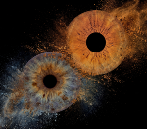 Dramatic "Iris Art" composition "Soul Fragment": two human eye irises (blue and amber) surrounded by a spectacular, contrasting smoke and dust explosion effect on a black background. This iris art online piece symbolizes spiritual searches and the merging of soul fragments. The online iris service allows you to order such personalized artworks online.