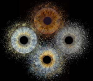 Powerful "Iris Photography online" artwork: four distinct human eye irises integrated into a dynamic explosion of dust and particles against a black background. Blue, brown, yellowish, and grey eyes merge into an energetic and dramatic artistic composition. This is unique iris art online, transforming the beauty of your eyes into a modern masterpiece. Use our online irises service and order such personalized artwork online.