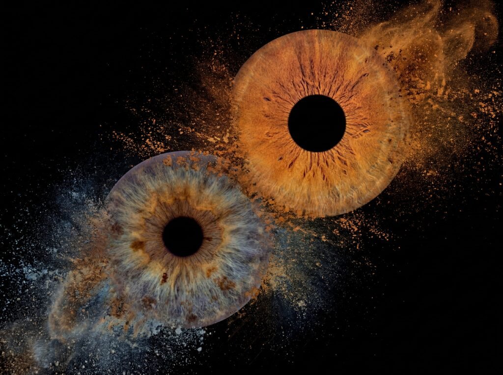 Elemental Drift custom couple iris art featuring two real eye irises surrounded by flowing elemental dust and atmospheric particles on a dark background.